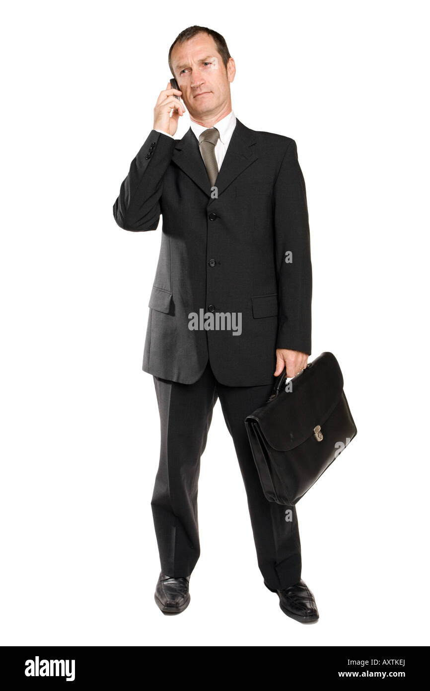 Homme d'affaires debout dans un costume noir tenant un téléphone portable dans sa main faisant un appel téléphonique parlant à quelqu'un un certain problème d'affaires. L'arrière-plan est blanc. Banque D'Images