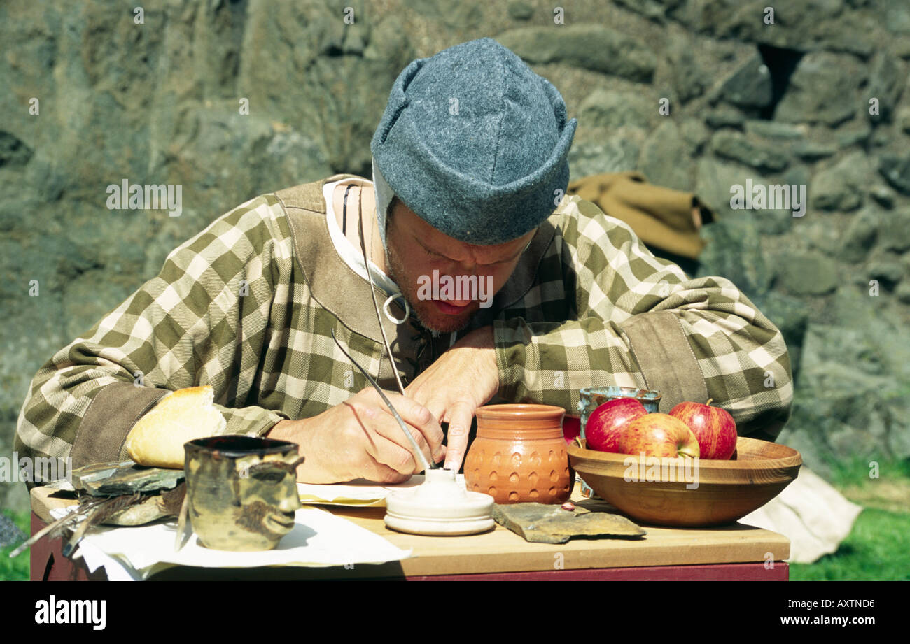 Homme habillé comme scribe et écrire avec une plume à une reconstitution historique Banque D'Images