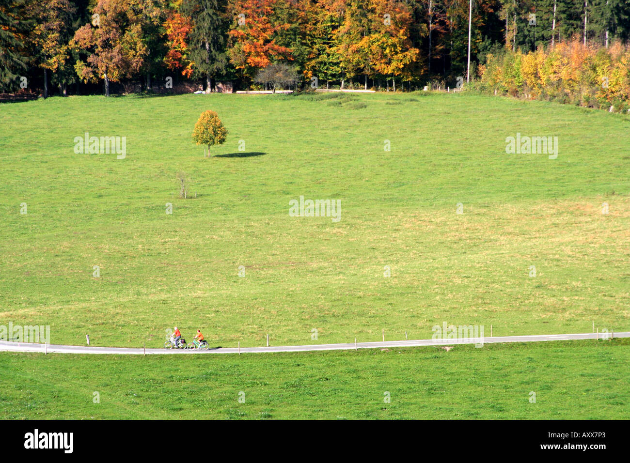 Deux cyclistes solitaires dans le lointain à travers un champ en Allemagne Bavière Bad Tolz Banque D'Images