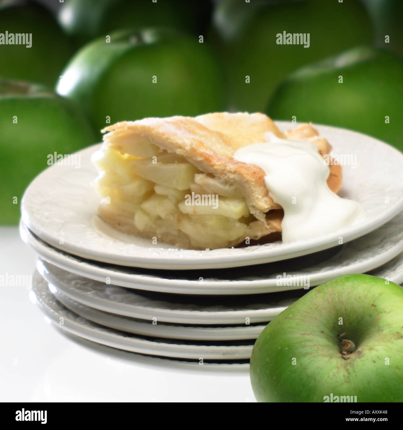 Portion de tarte aux pommes et crème fraîche sur la pile de plaques blanches avec pommes Bramley autour Banque D'Images