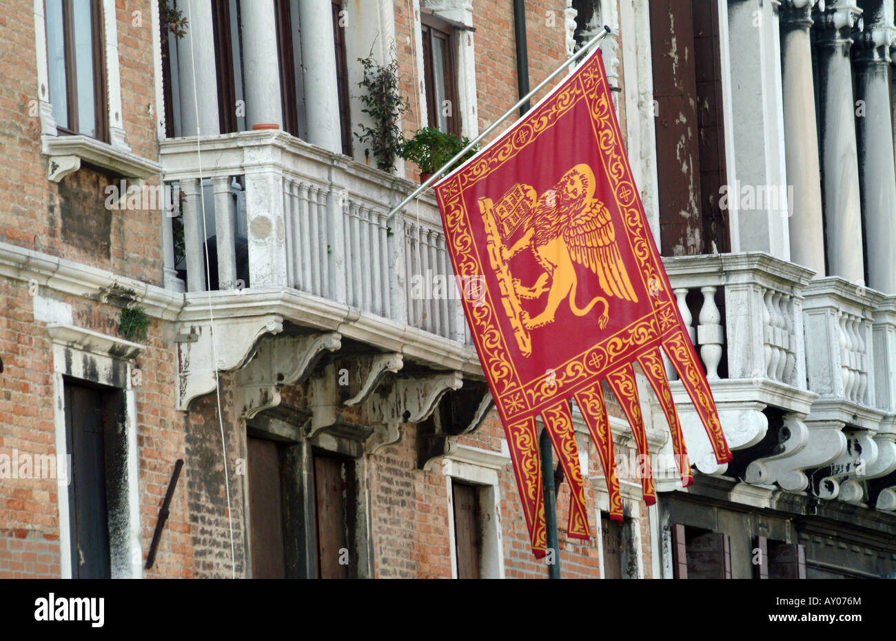 Drapeau vénitien du lion d'or sur fond rouge battant depuis le balcon de l'immeuble sur Grand Canal, Venise, Italie Banque D'Images