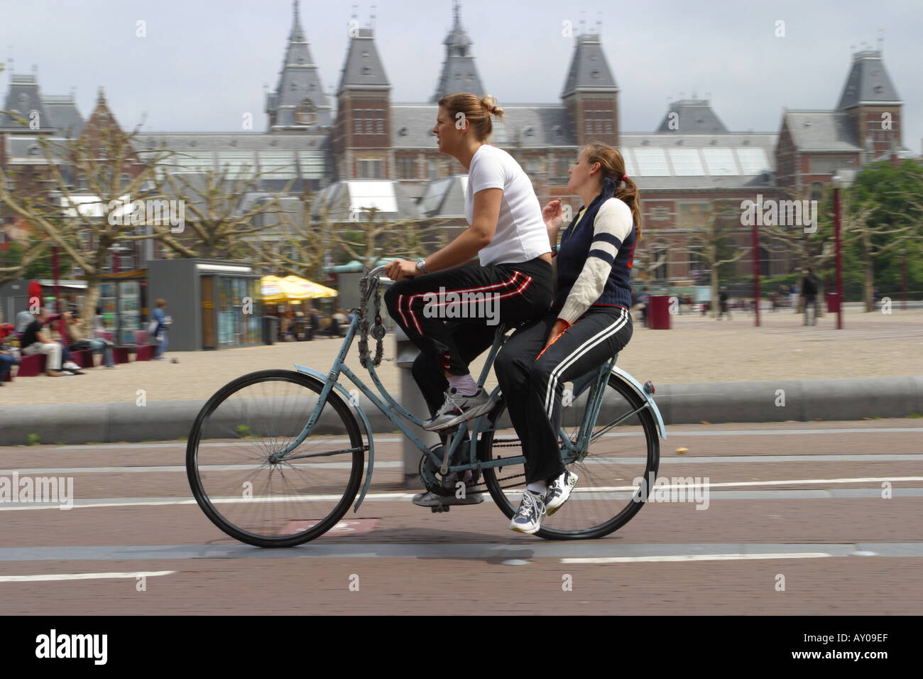Deux jeunes femmes partagent un vélo comme ils le cycle passé Rijksmuseum à Amsterdam Pays-Bas Banque D'Images