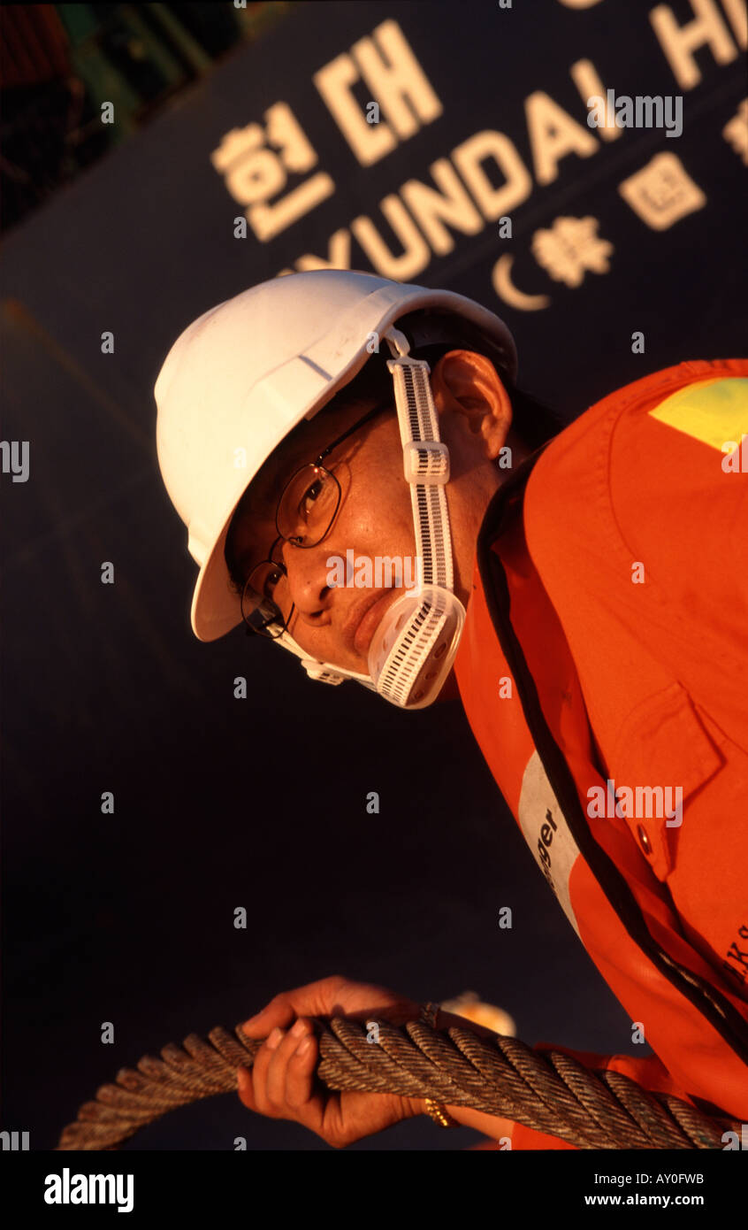 Close up of face de tugboat worker holding prêts à passer la ligne d'amarrage jusqu'à porte-conteneurs à Kwai Chung hong kong port fareast Banque D'Images