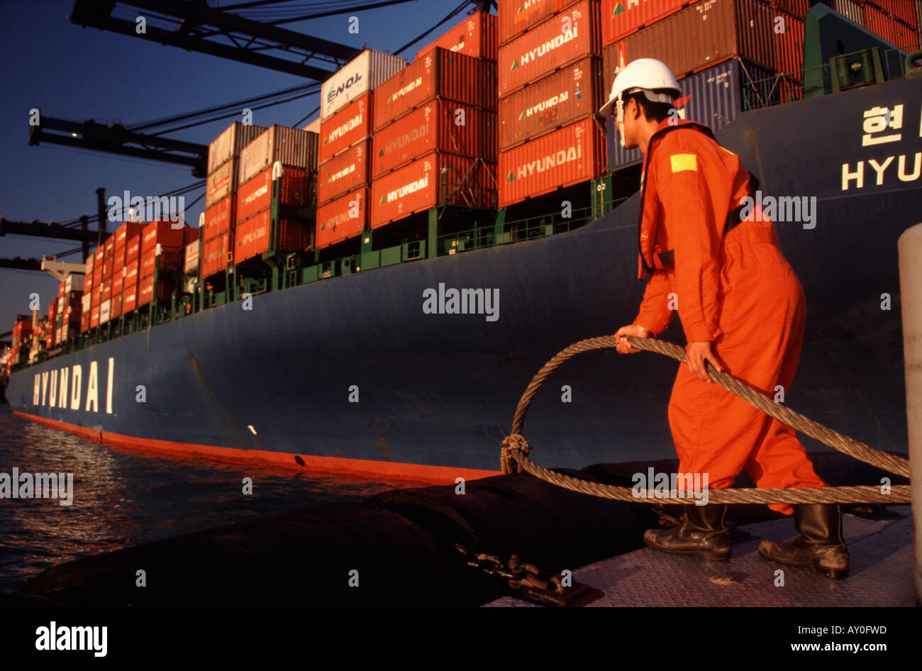 Tugboat worker holding prêts à passer la ligne d'amarrage jusqu'à porte-conteneurs à Kwai Chung hong kong port fareast Asie Banque D'Images