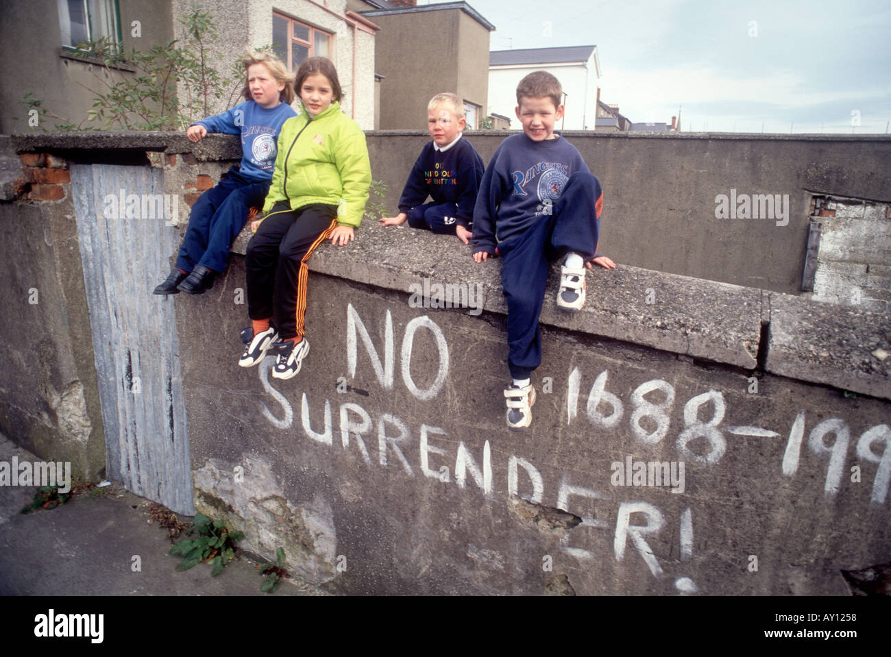 De vrais enfants locaux avec le message de l'IRA à Derry, Irlande du Nord Londonderry Royaume-Uni tué avec aucun signe peint de reddition sur le mur Banque D'Images