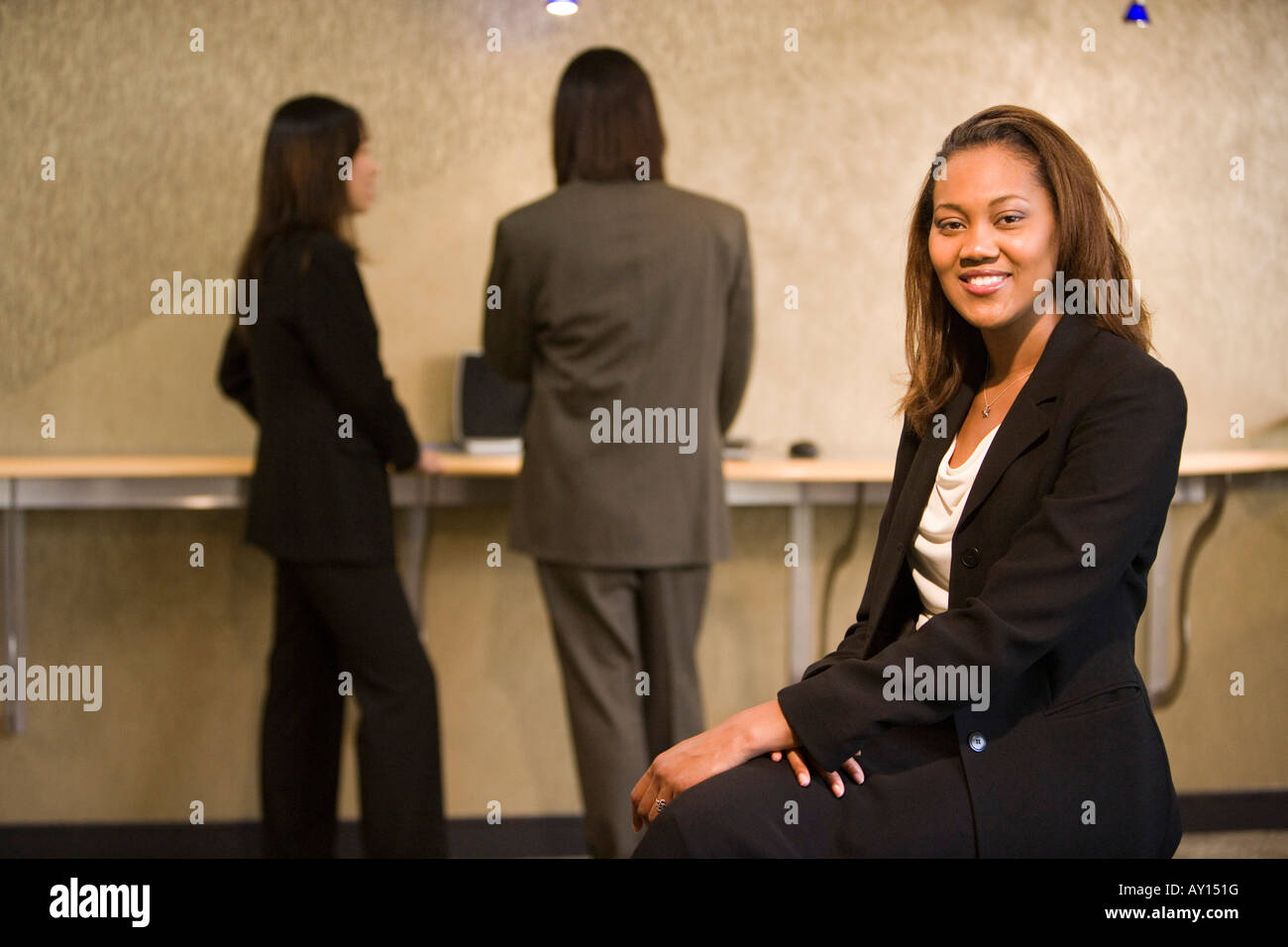 Portrait of a cheerful businesswoman sitting pendant que ses collègues debout à l'arrière-plan Banque D'Images