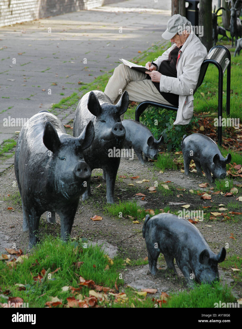 Un homme écrit son journal par des sculptures de porcs sur la rive sud de la Tamise à Londres Banque D'Images