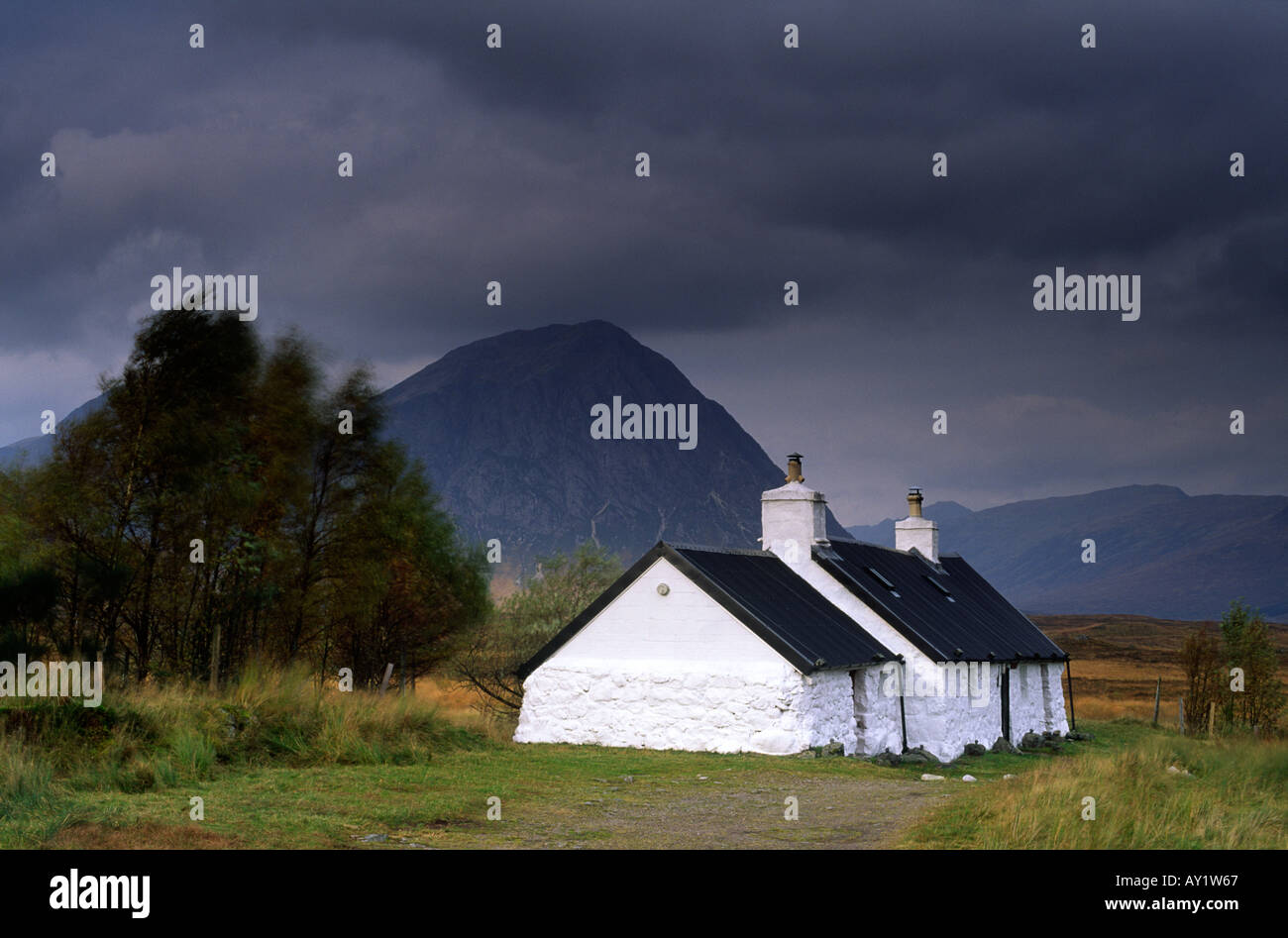 Black Rock Cottage éclairée par le soleil sur une journée venteuse et moody à Glen Coe dans les Highlands écossais UK Banque D'Images