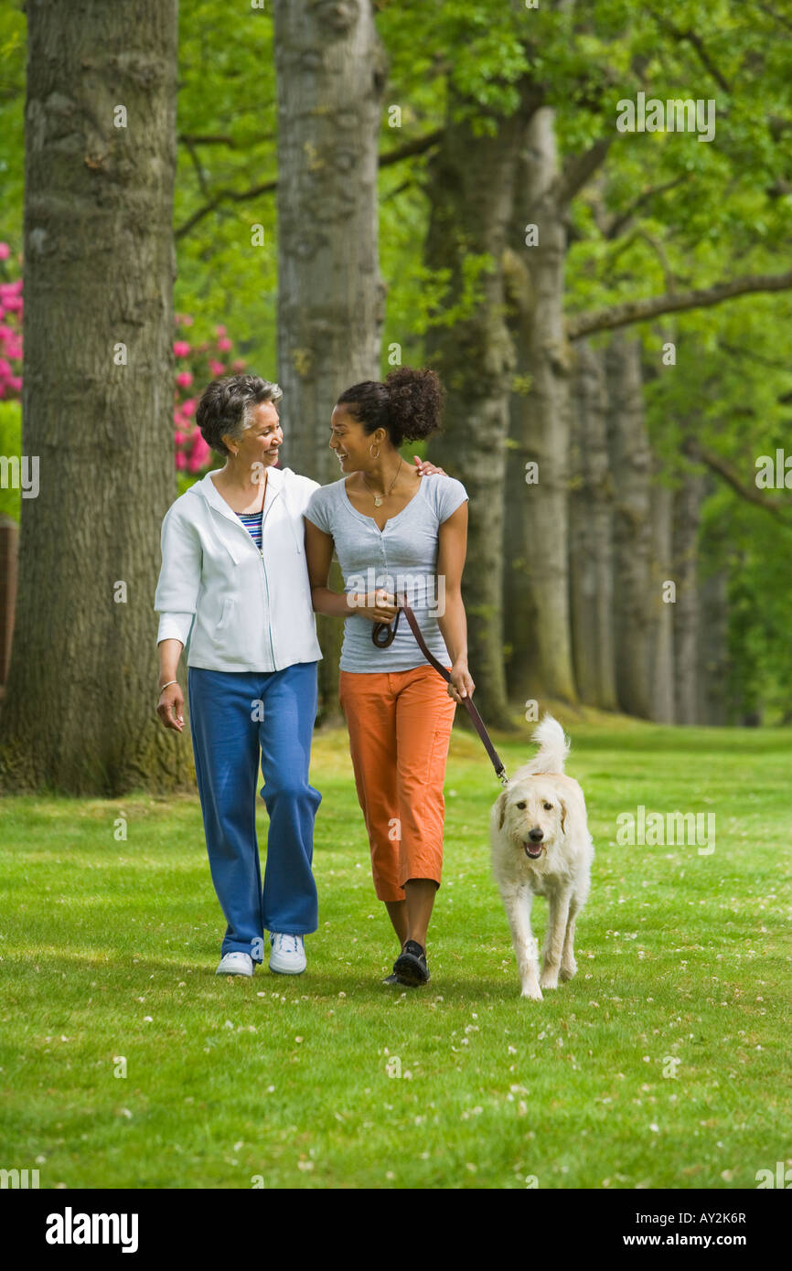 African American mother and daughter walking dog Banque D'Images
