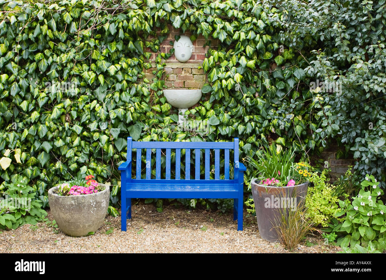 Jardin en bois peint bleu siège en face de la fontaine murale Banque D'Images