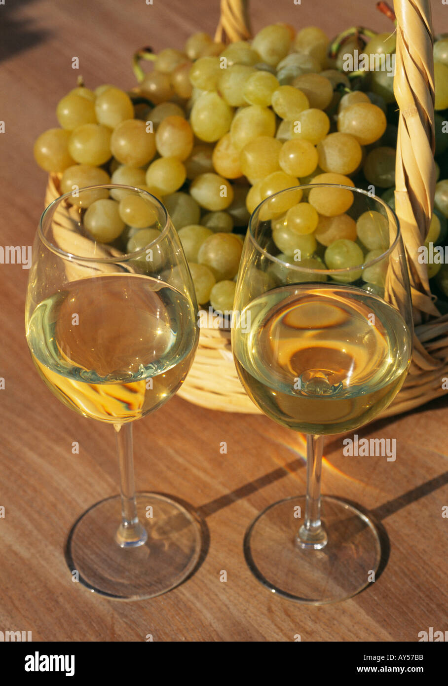 Deux verres de vin blanc avec des raisins récoltés à la main dans un panier en osier Banque D'Images