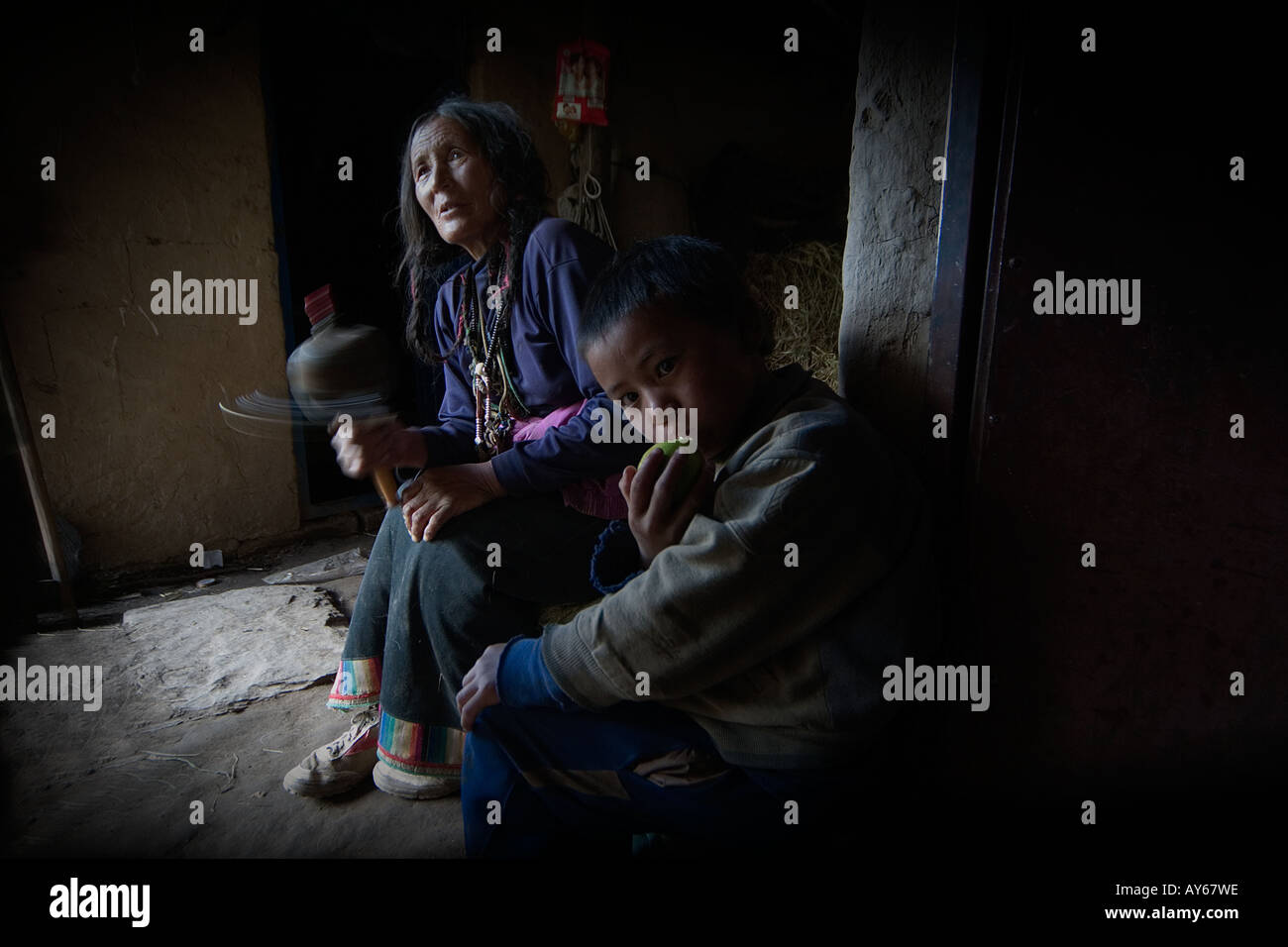 Une femme tibétaine est à sa prière avec une roue dans la prière. Banque D'Images