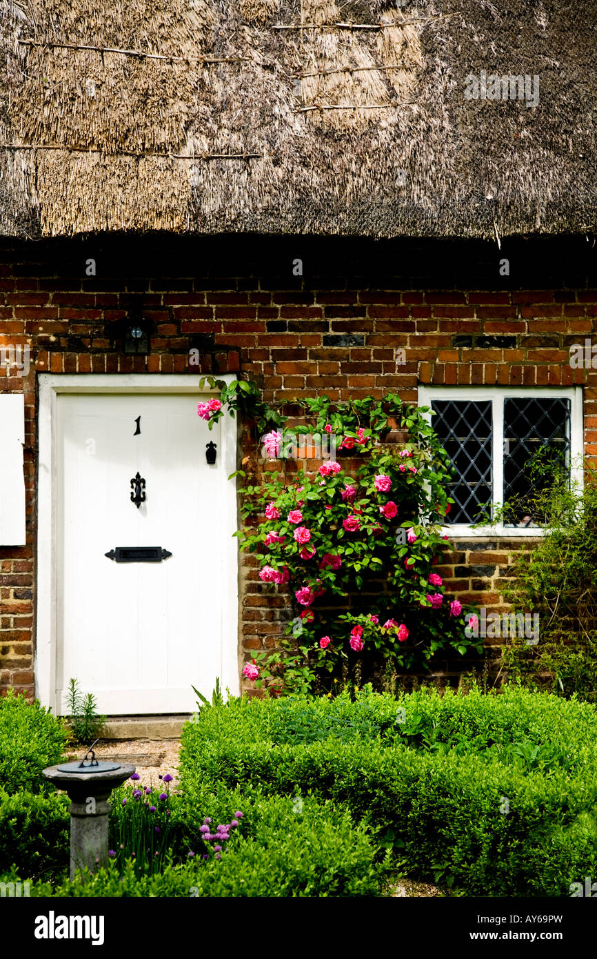 La porte avant, un toit de chaume et fenêtre d'un cottage anglais traditionnel avec de plus en plus roses roses sur la porte Banque D'Images