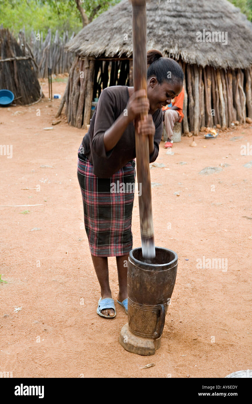 Fille namibienne pounding manioc dans un bol en bois avec pilon stick Banque D'Images