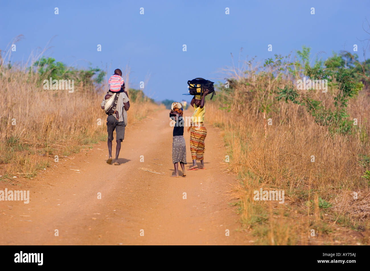 Petites balades familiales à leur nouvelle maison sur un chemin de poussière rouge en Amérique du Mozambique Banque D'Images