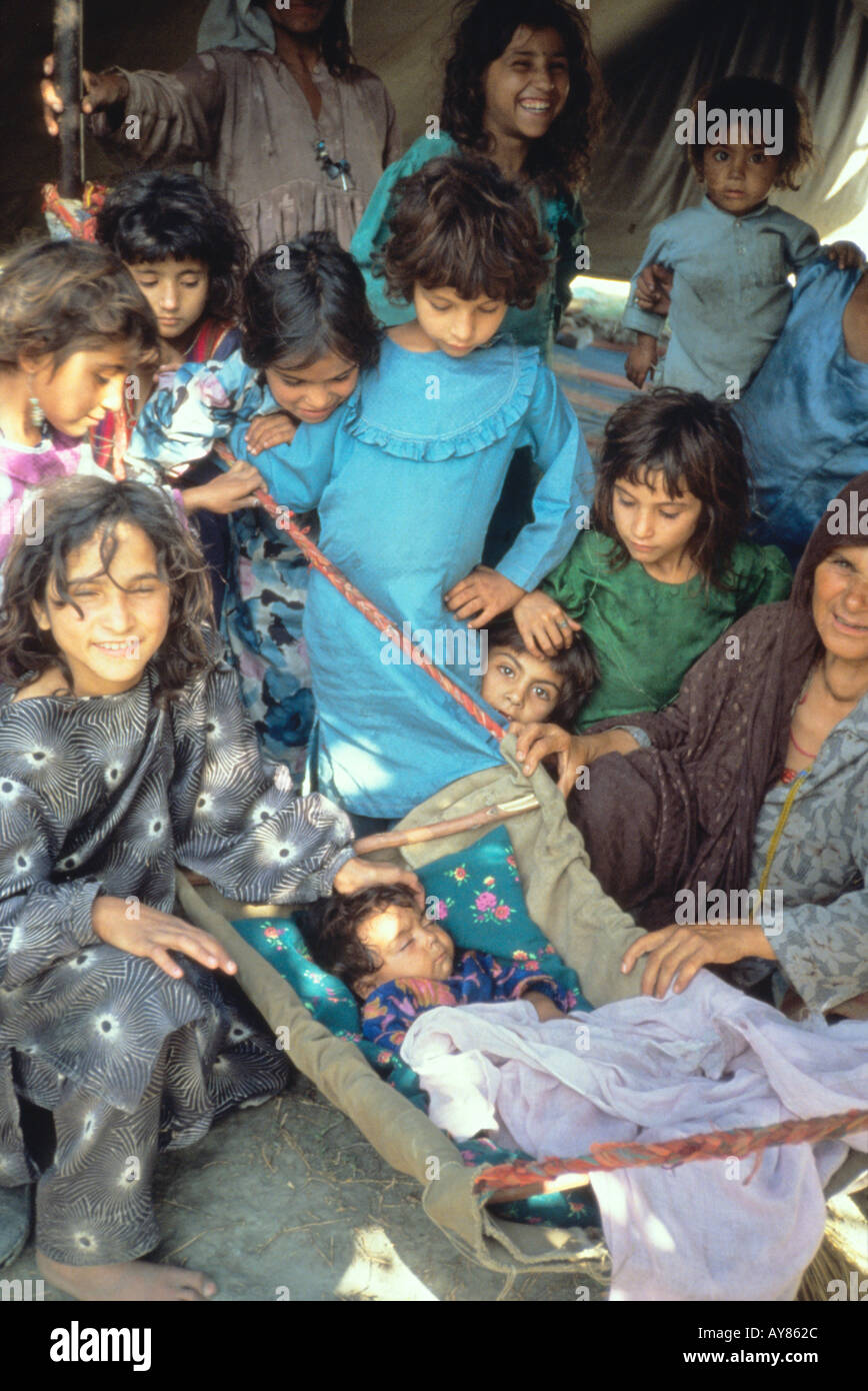 Les enfants admirer bébé dans une tente dans le camp de réfugiés afghans au Pakistan Chitral Banque D'Images
