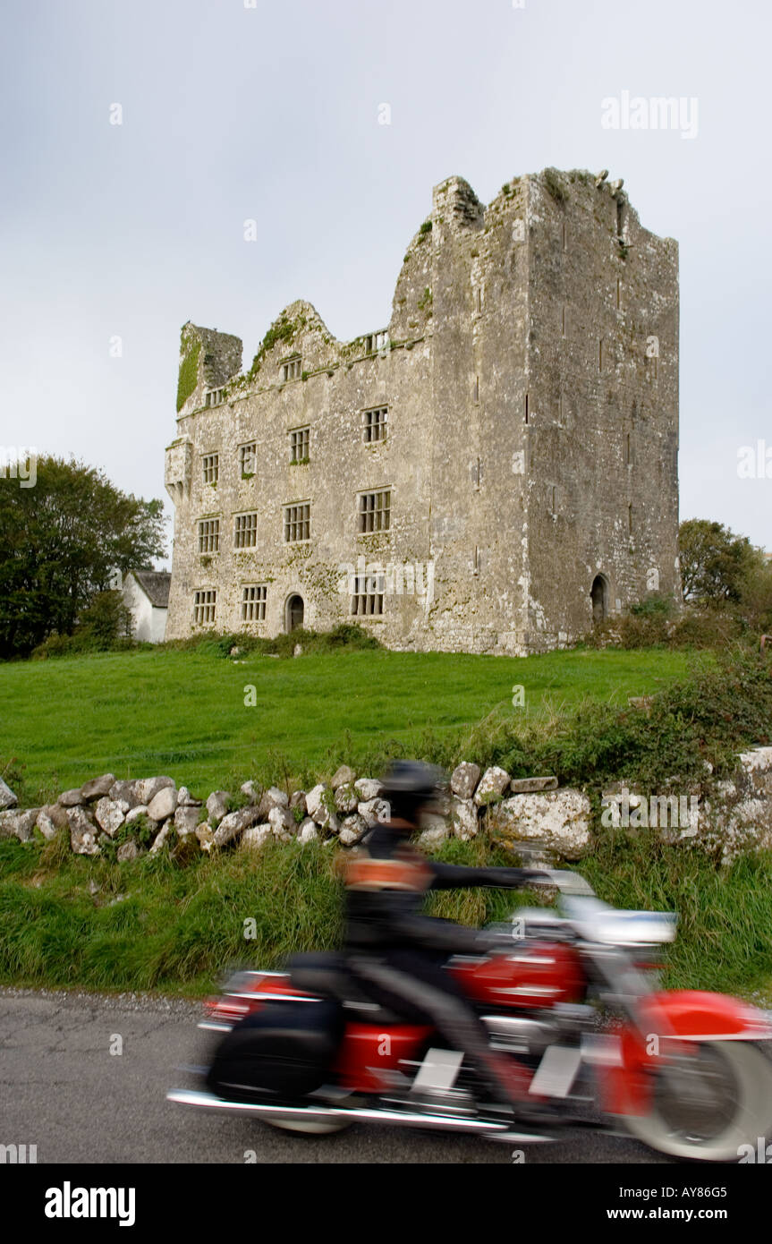 L'homme sur classic touring moto moto passé Leamaneh Castle, comté de Clare, Irlande Banque D'Images