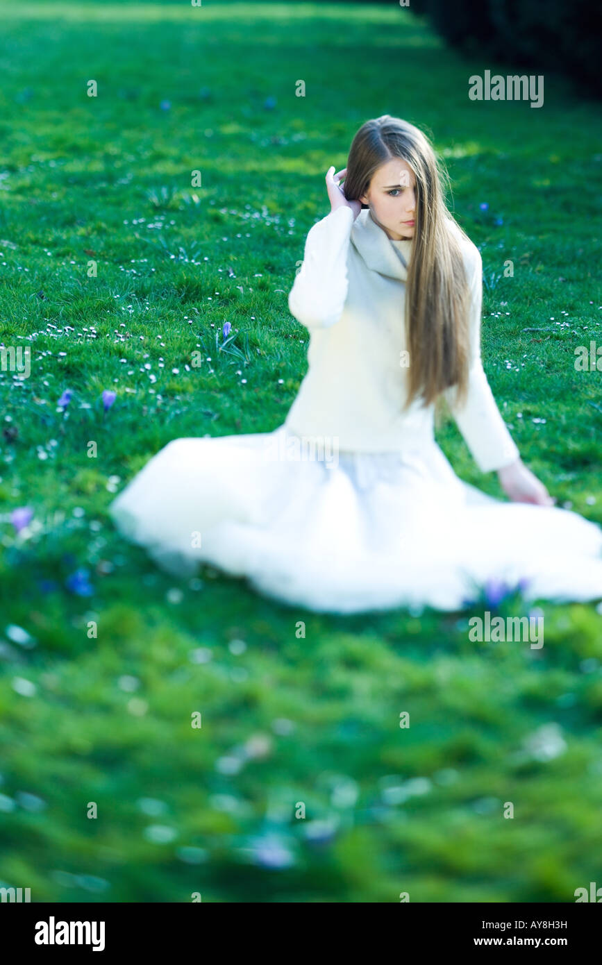 Teenage girl sitting in grass, les cheveux couvrant partiellement le visage, à l'écart Banque D'Images