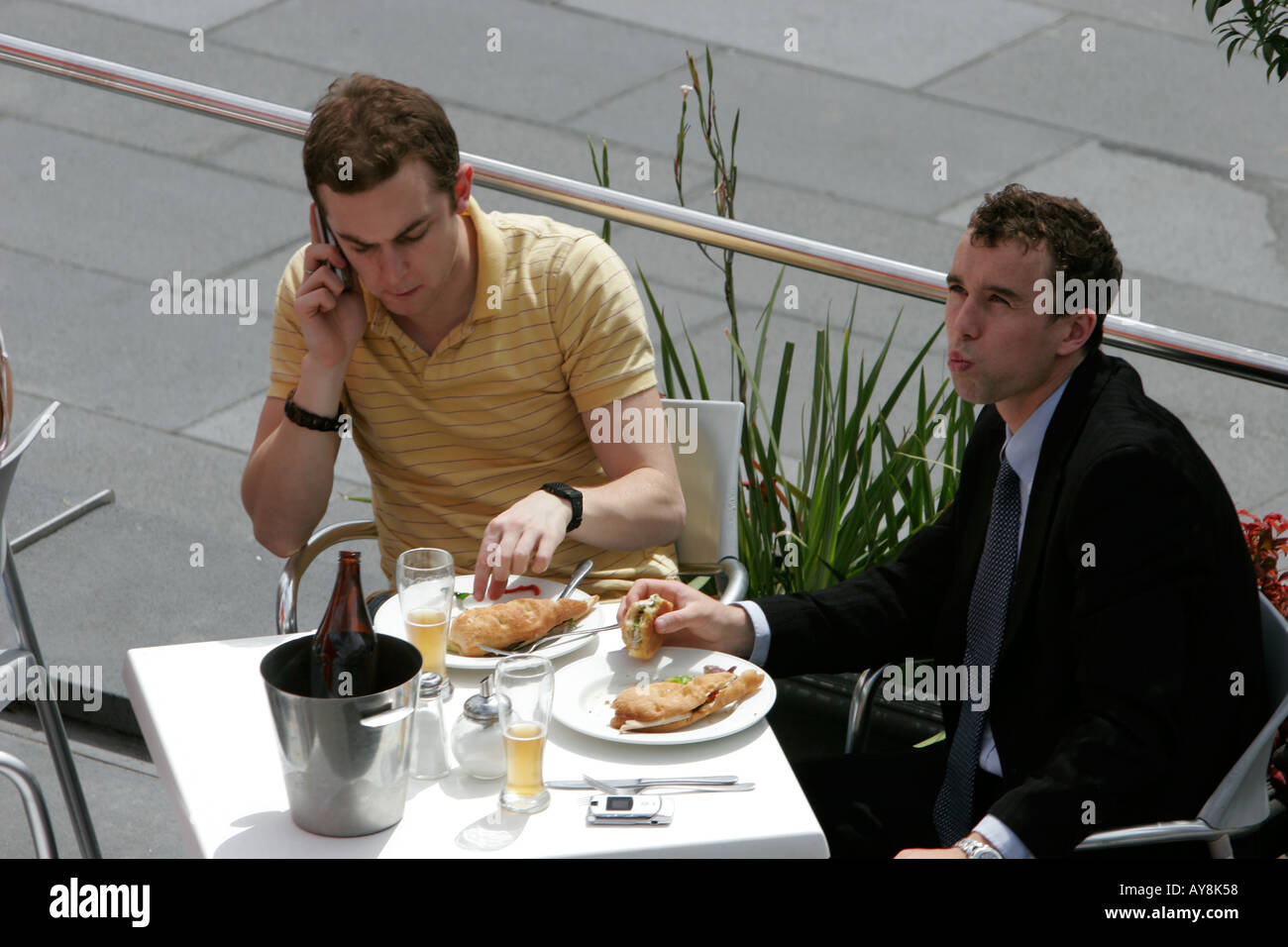 Déjeuner sandwich pour deux hommes avec les téléphones mobiles Melbourne Australie Victoria Banque D'Images