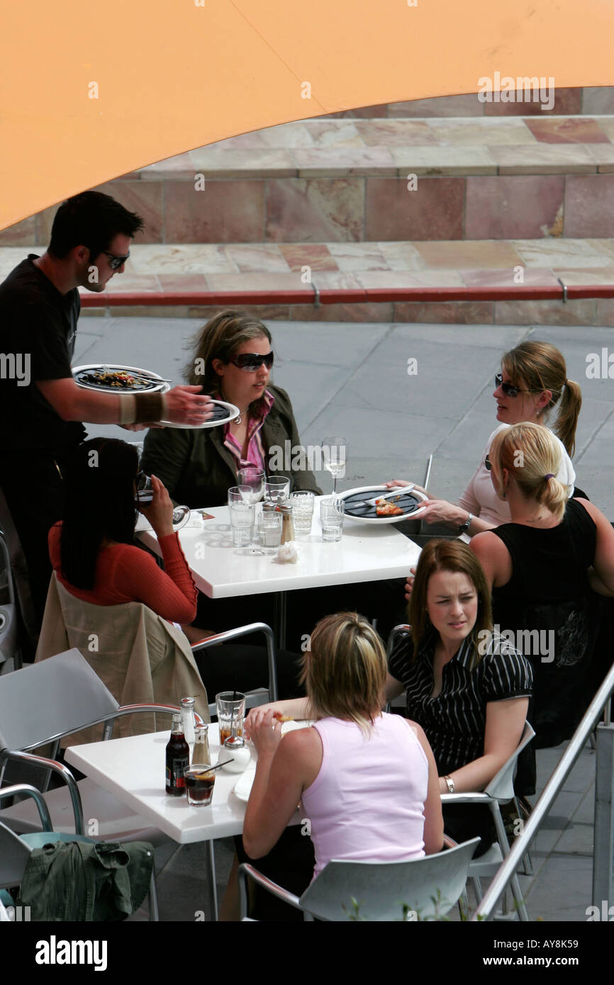 Garçon assiste à de jeunes femmes en train de dîner à l'extérieur de Melbourne, Victoria Australie Banque D'Images