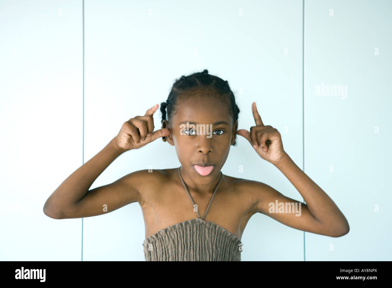 Little girl sticking tongue out at camera, bras levés, portrait Banque D'Images
