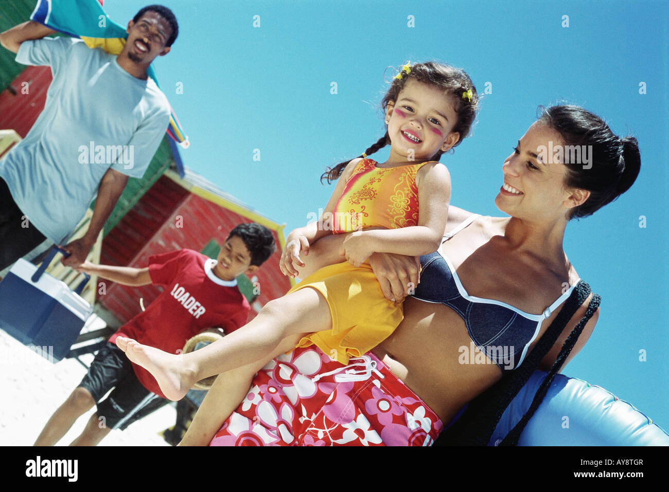 Balades en famille à la plage, maman de transporter sa fille, girl smiling at camera Banque D'Images