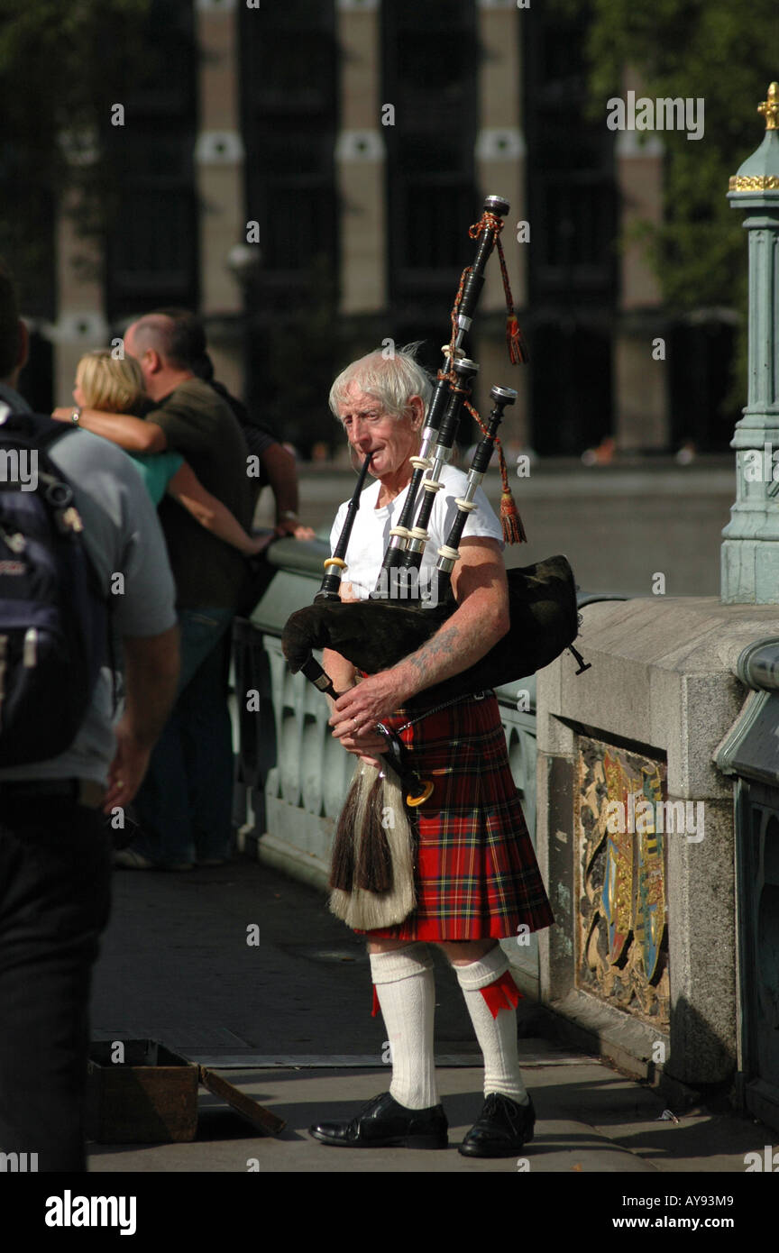 Vieil homme en jouant de la cornemuse écossaise pour l'usure de l'argent sur le pont de Westminster à Londres Banque D'Images