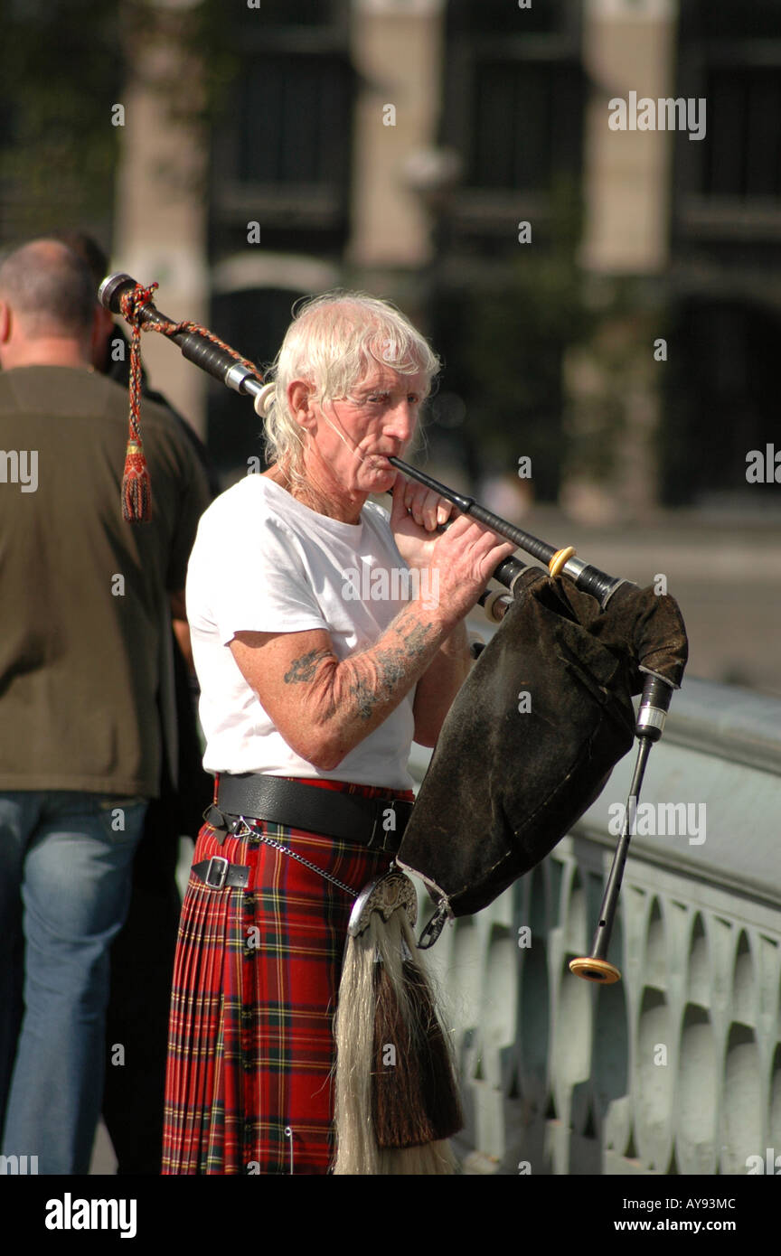 Vieil homme en jouant de la cornemuse écossaise pour l'usure de l'argent sur le pont de Westminster à Londres Banque D'Images