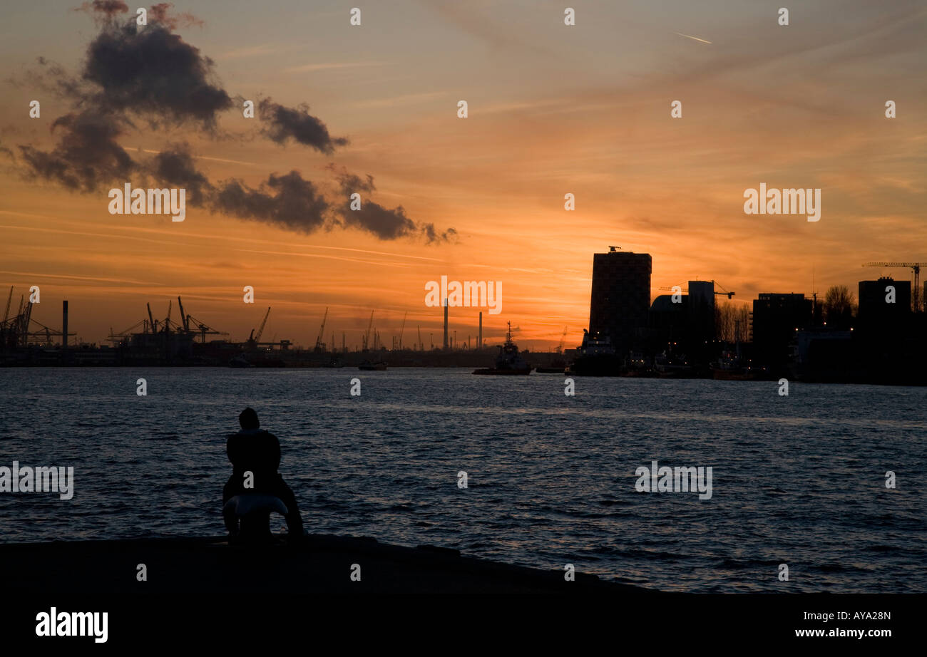 Un homme prend une pause Meuse au coucher du soleil Banque D'Images