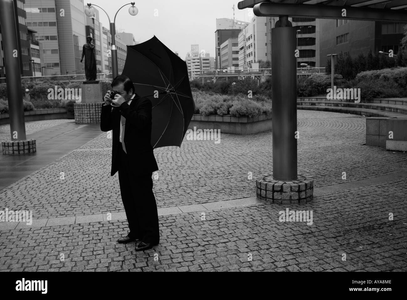 Asie Tokyo Japon Man in suit en prenant des instantanés dans la pluie Banque D'Images