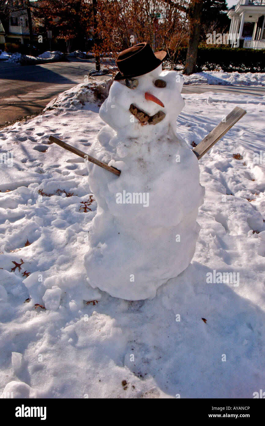 Un bonhomme de neige classique avec des pierres pour les yeux et la bouche une carotte pour un nez et décoré dans un vieux chapeau Banque D'Images Un bonhomme de neige classique avec des pierres pour les yeux et la bouche une carotte pour un nez et décoré dans un vieux chapeau Banque D'Images
