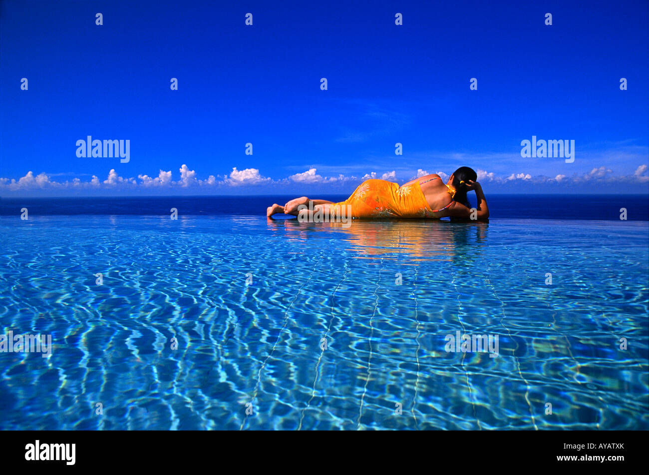 Woman in swimming pool overlooking ocean, Bali, Indonésie Banque D'Images