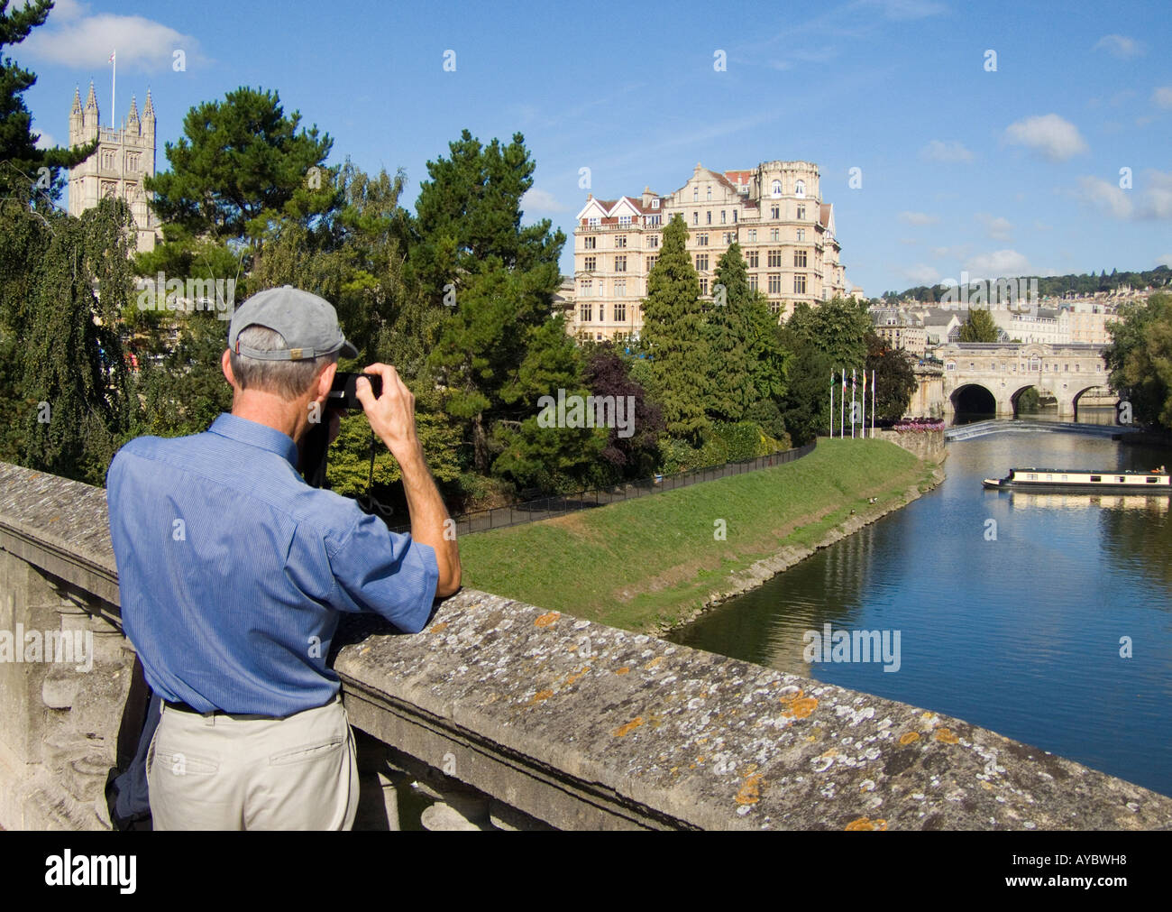 Un touriste photographies à partir d'un pont sur la rivière Avon à Bath Banque D'Images