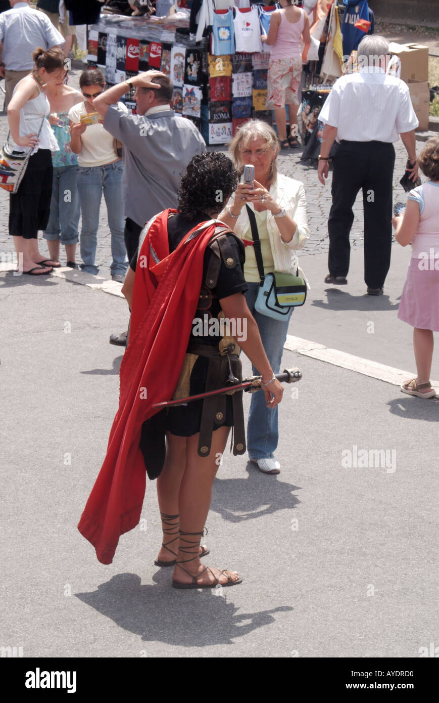 Rome scène de rue bondée homme habillé en soldat centurion et facturant une taxe pour les touristes prenant des photos à l'extérieur du Colisée Italie Banque D'Images