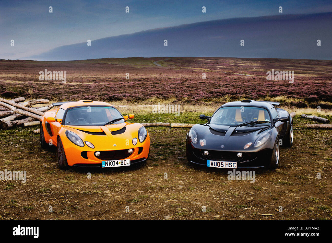 Deux voitures Lotus exige, une orange et une noire garées côte à côte avec le paysage spectaculaire des North Yorkshire Moors au loin. Banque D'Images
