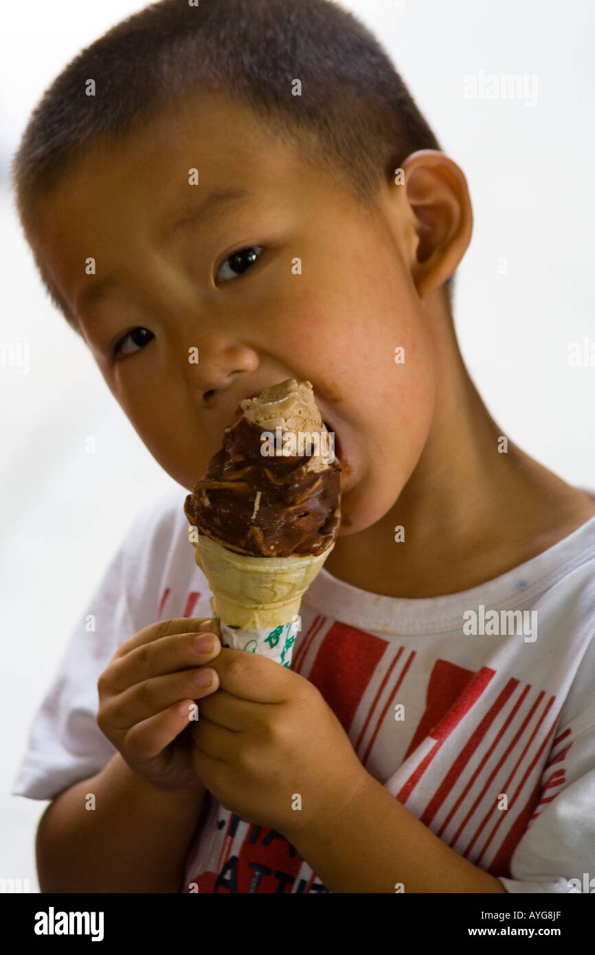 Jeune chinois enfant mange une crème glacée au chocolat au chocolat Cone, Beijing, Chine Banque D'Images