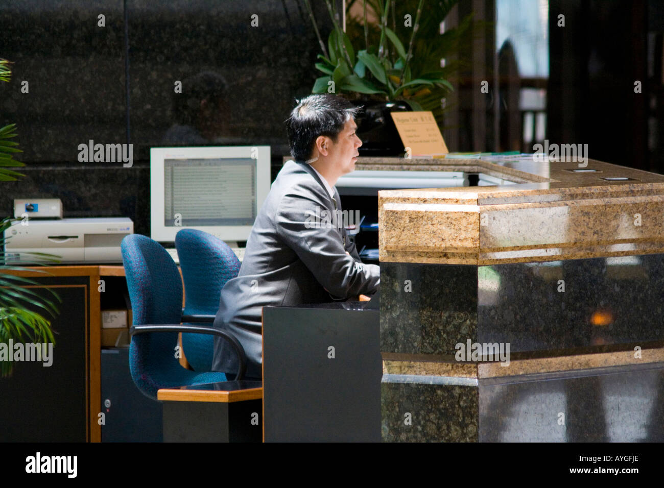 Asian homme est assis derrière un bureau à l'entrée d'un bâtiment Hong Kong Chine Banque D'Images