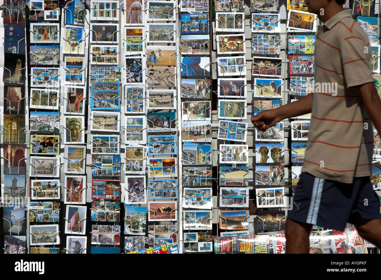 Jeune homme passe grand appartement de vacances post card rack Sousse Tunisie Banque D'Images