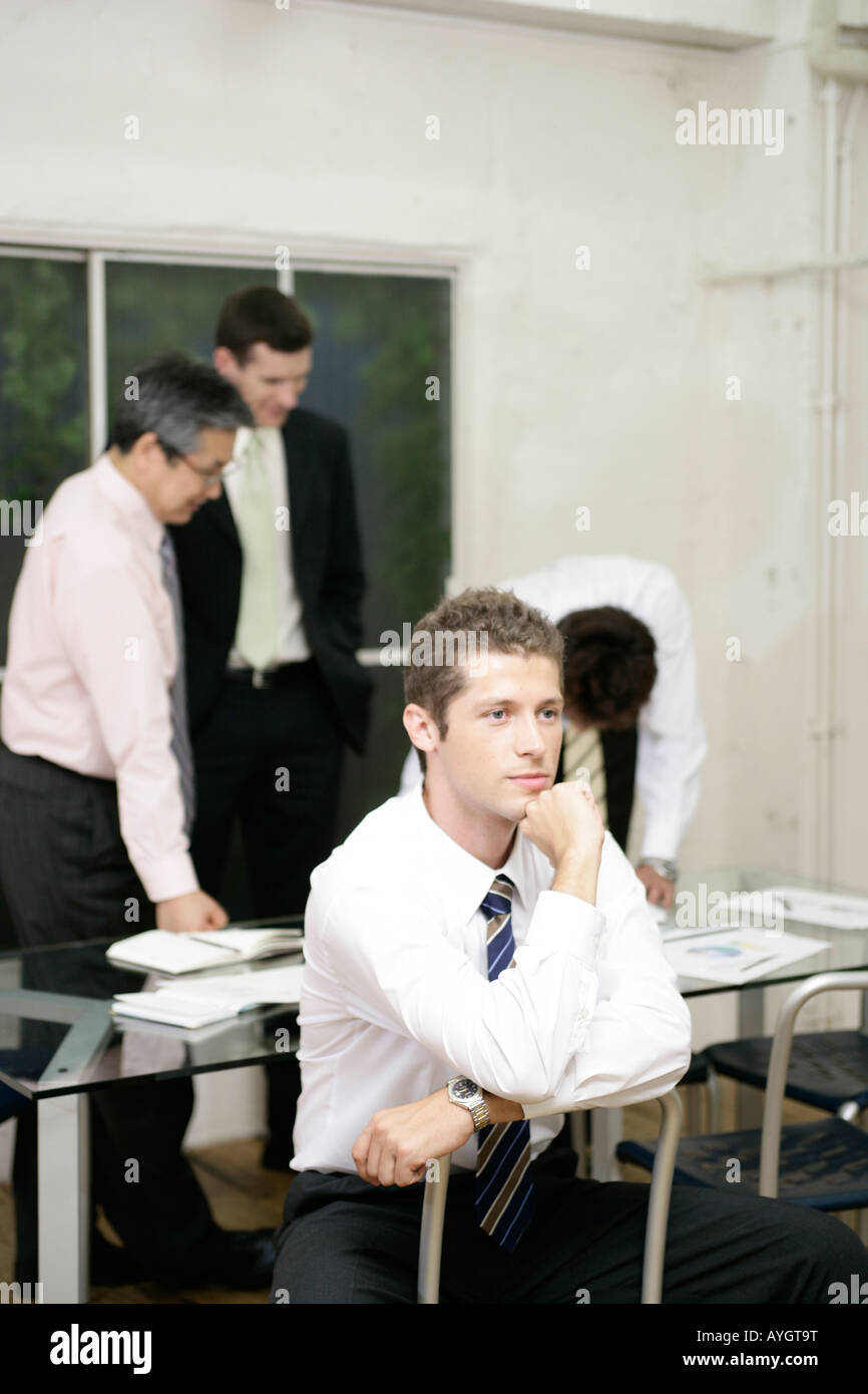 Businessman sitting on chair avec trois collègues sur l'arrière-plan Banque D'Images