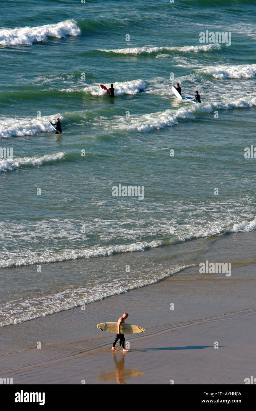 Un internaute quitte la mer avec sa planche de surf sous le bras Banque D'Images