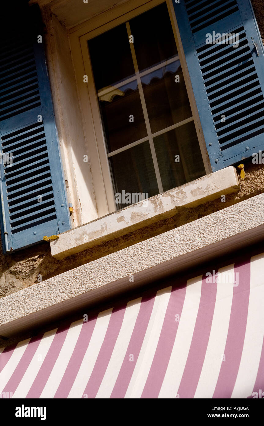 Jusqu'à la fenêtre à volets au-dessus d'un magasin et rose à rayures auvent blanc à Sanary sur Mer, France Banque D'Images