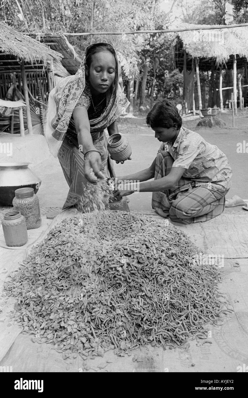B/W d'une mère et d'un fils mélangeant des ingrédients pour la production de collations à petite échelle dans le cadre d'un programme de génération de revenus sur l'île Sandwip. Baie du Bengale, Bangladesh Banque D'Images