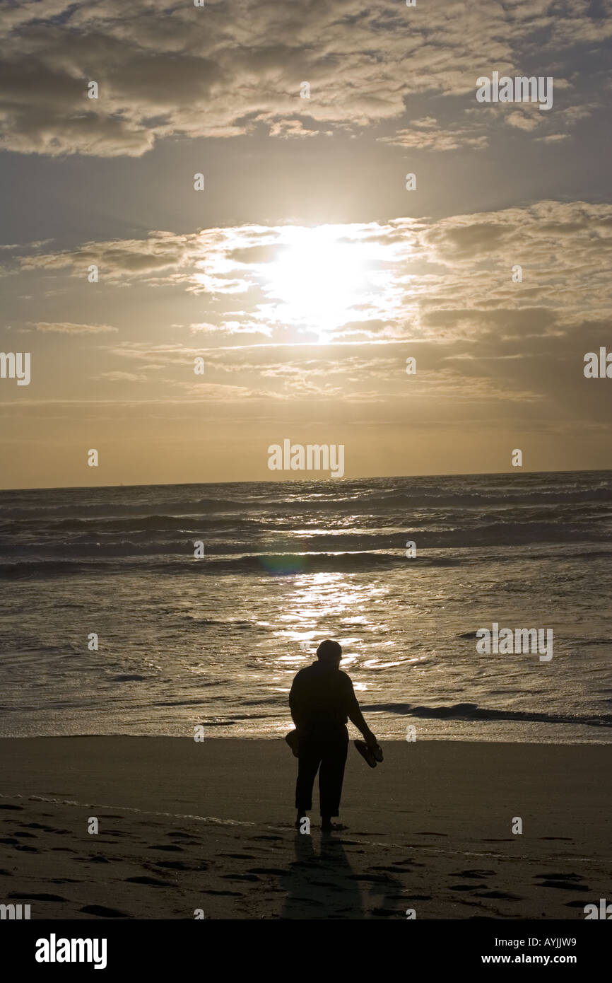 Silhouette d'homme qui regarde le soleil au-dessus de la mer et de la plage Praia de Mira Portugal Banque D'Images