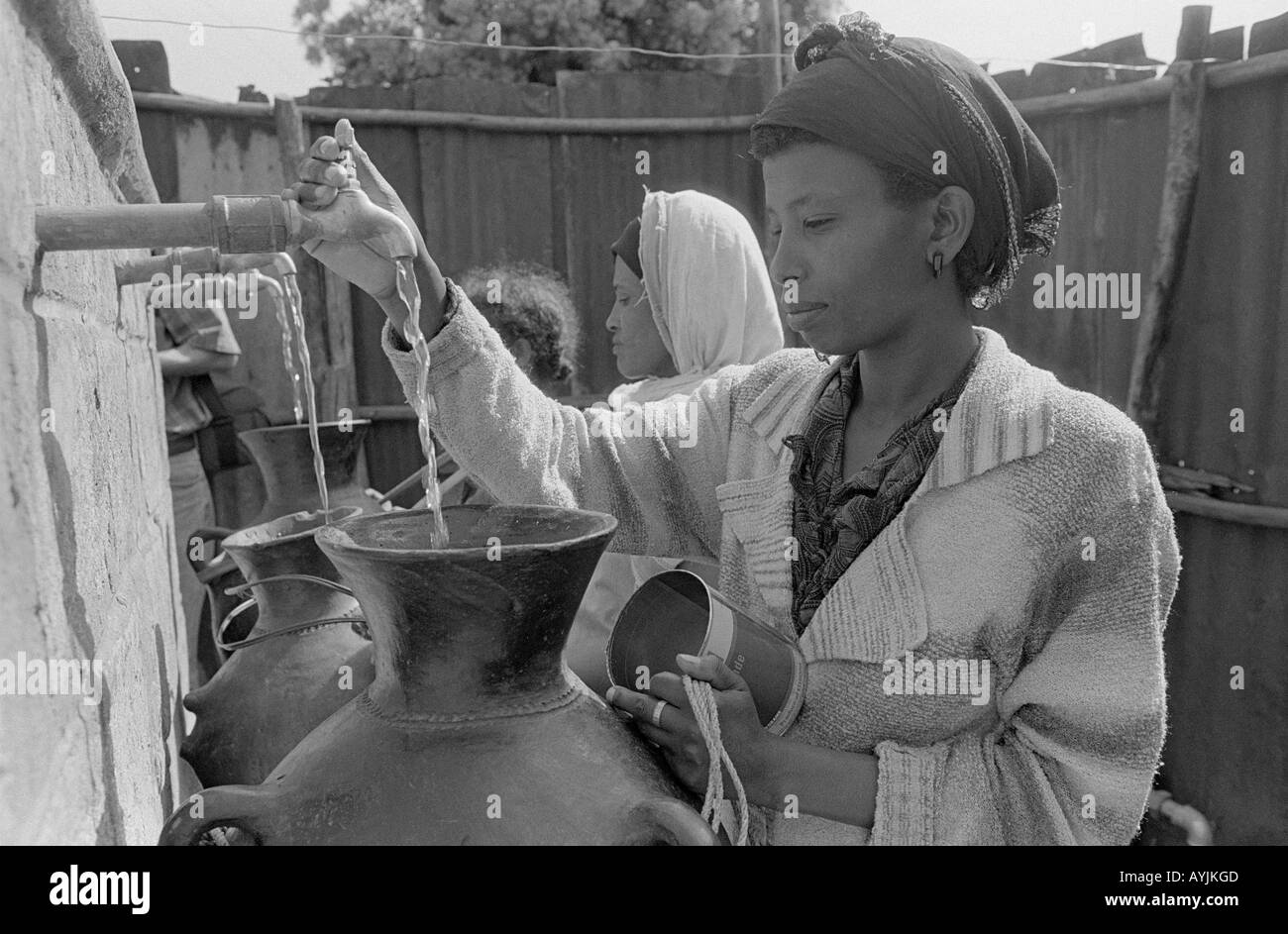 B/W des femmes rurales qui collectent de l'eau dans de grands bocaux à des robinets à partir d'un ressort bouché.Tigray, Éthiopie, Afrique Banque D'Images