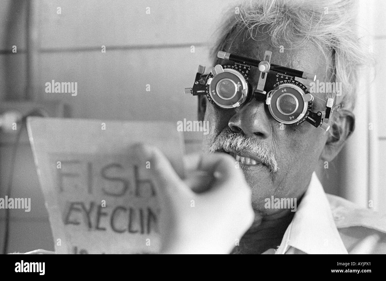 B/W d'un homme âgé qui lit une carte de test oculaire dans une clinique de Kingston. Jamaïque Banque D'Images