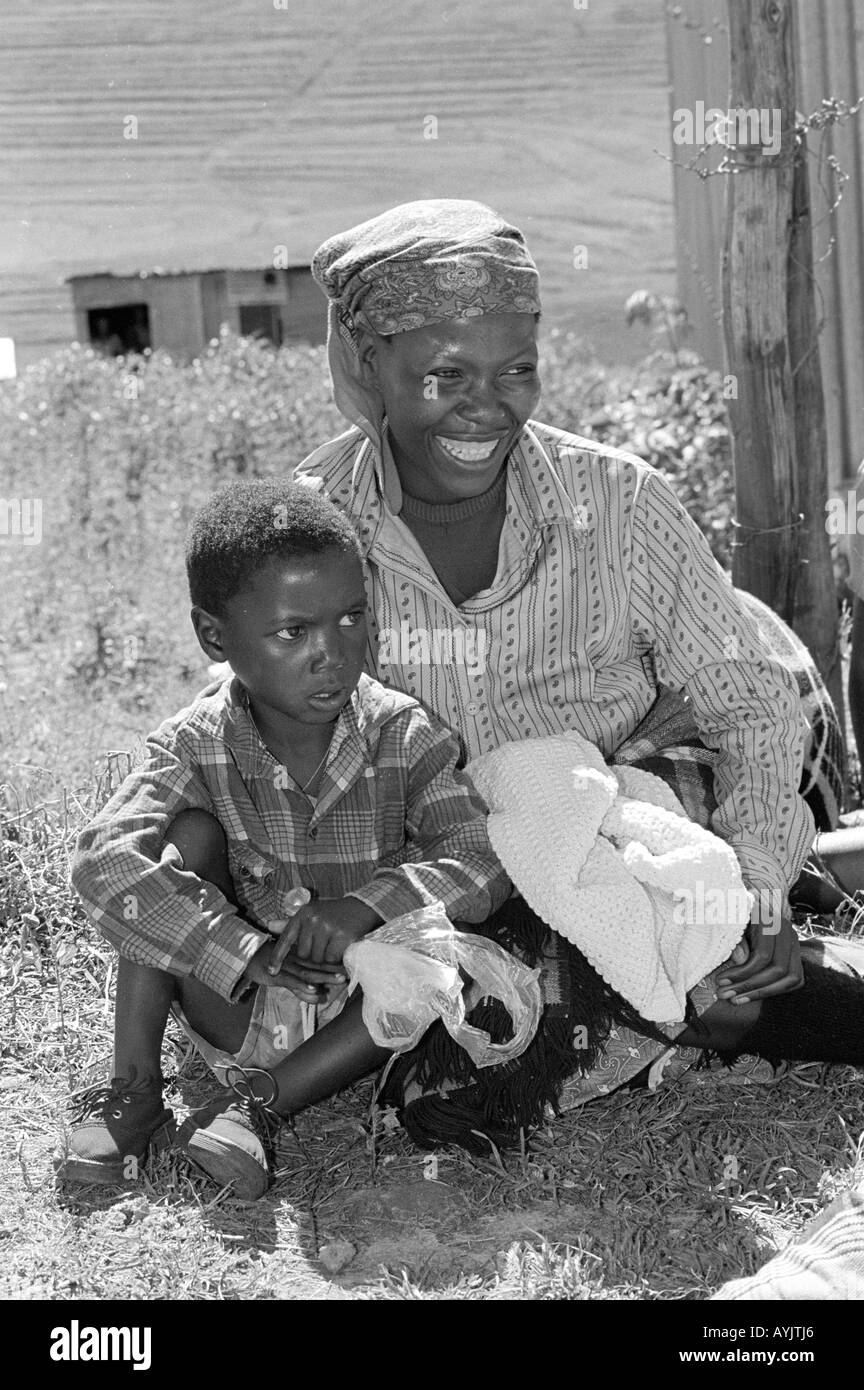 B/W d'une mère et d'un enfant en attente de farine de maïs dans un centre d'aide alimentaire pendant une période de sécheresse. White Hil, Lesotho Banque D'Images