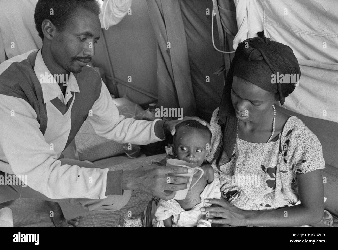 B/W d'un travailleur de l'aide qui nourrit un enfant malnutris dans un centre d'alimentation pour réfugiés.Kebrebeyah, Éthiopie, Afrique Banque D'Images