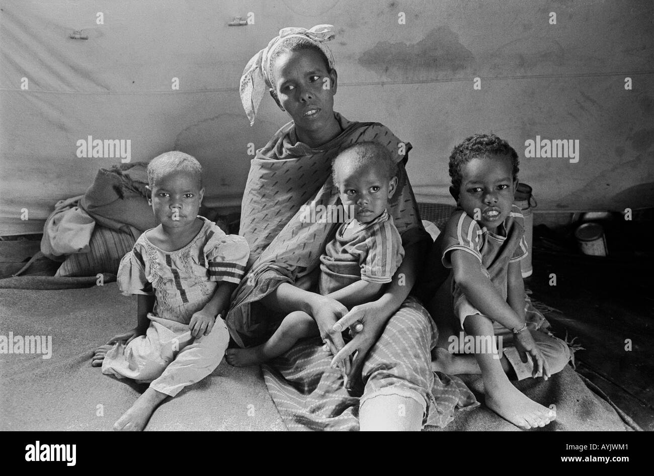 B/W d'une femme somalienne avec trois enfants malnutris assis sur le terrain dans un centre d'alimentation d'urgence pour les réfugiés.Kebrebeyah, Éthiopie, Afrique Banque D'Images