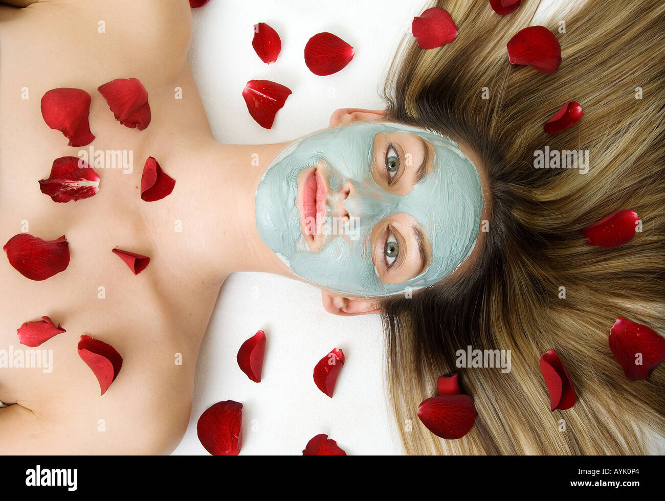 Femme avec visage boue marine et pétales de rose Banque D'Images