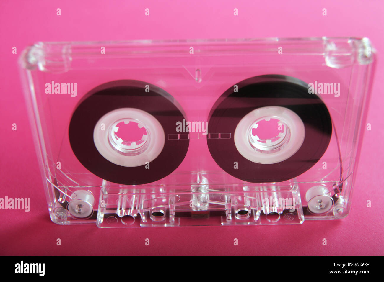 Cassette audio transparent sur fond rose. Banque D'Images